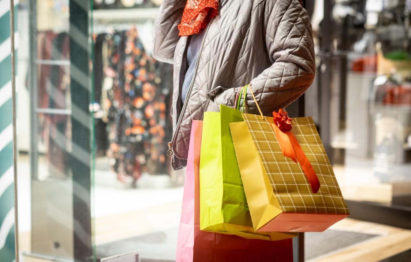 close-up-of-a-woman-holding-shopping-bags-looking-at-shop-window-overspending-money