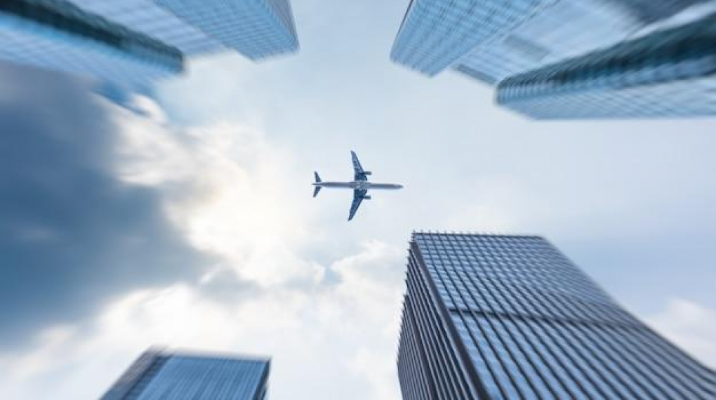 plane flying between on top of high buildings