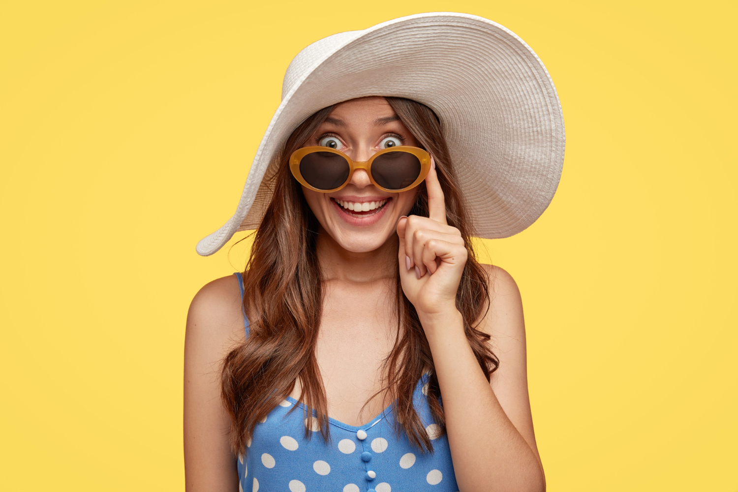 fashionable-lady-with-glad-expression-wears-white-hat-sunglasses-finds-hotel-stay-during-vacation-ready-go-beach-isolated-yellow-wall-tourism-summer-time-concept
