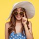 fashionable-lady-with-glad-expression-wears-white-hat-sunglasses-finds-hotel-stay-during-vacation-ready-go-beach-isolated-yellow-wall-tourism-summer-time-concept